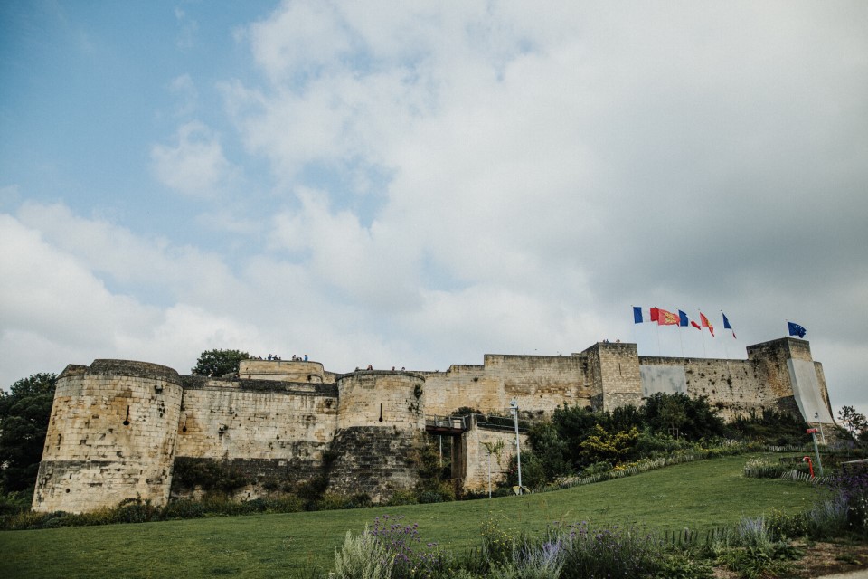 Le château de Caen entouré de drapeaux et d'espaces verts.