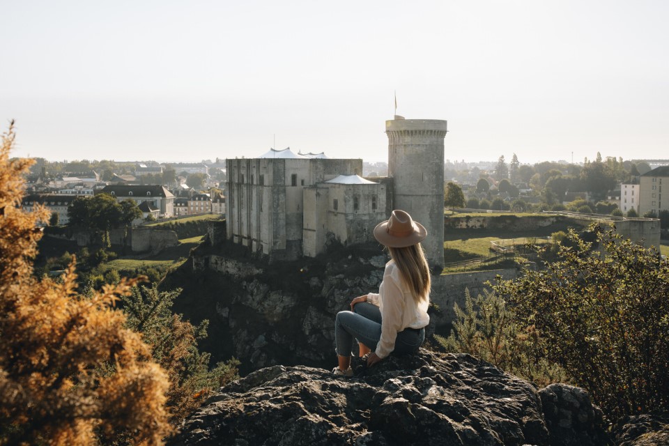 Vue sur le château de Falaise avec une femme admirant la forteresse.