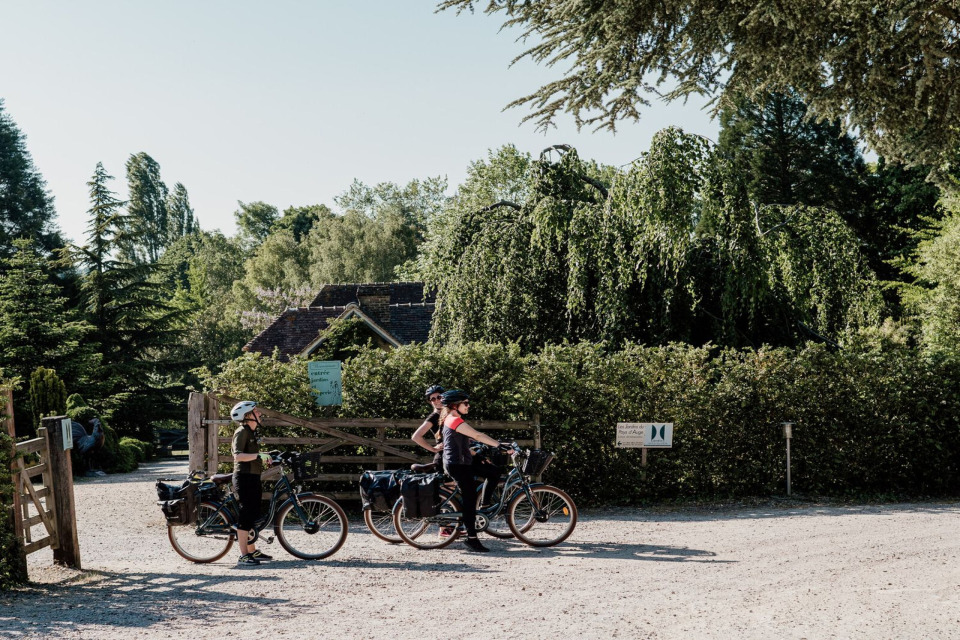 Cyclistes devant les Jardins du Pays d'Auge, un cadre rustique et verdoyant.