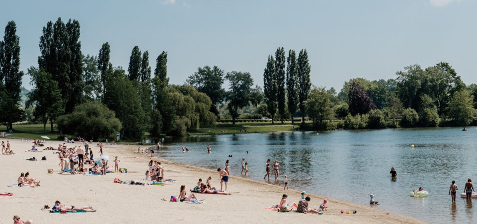 Plage du lac de Pont-l'Évêque, idéale pour la baignade et la détente en famille, entourée de nature verdoyante.